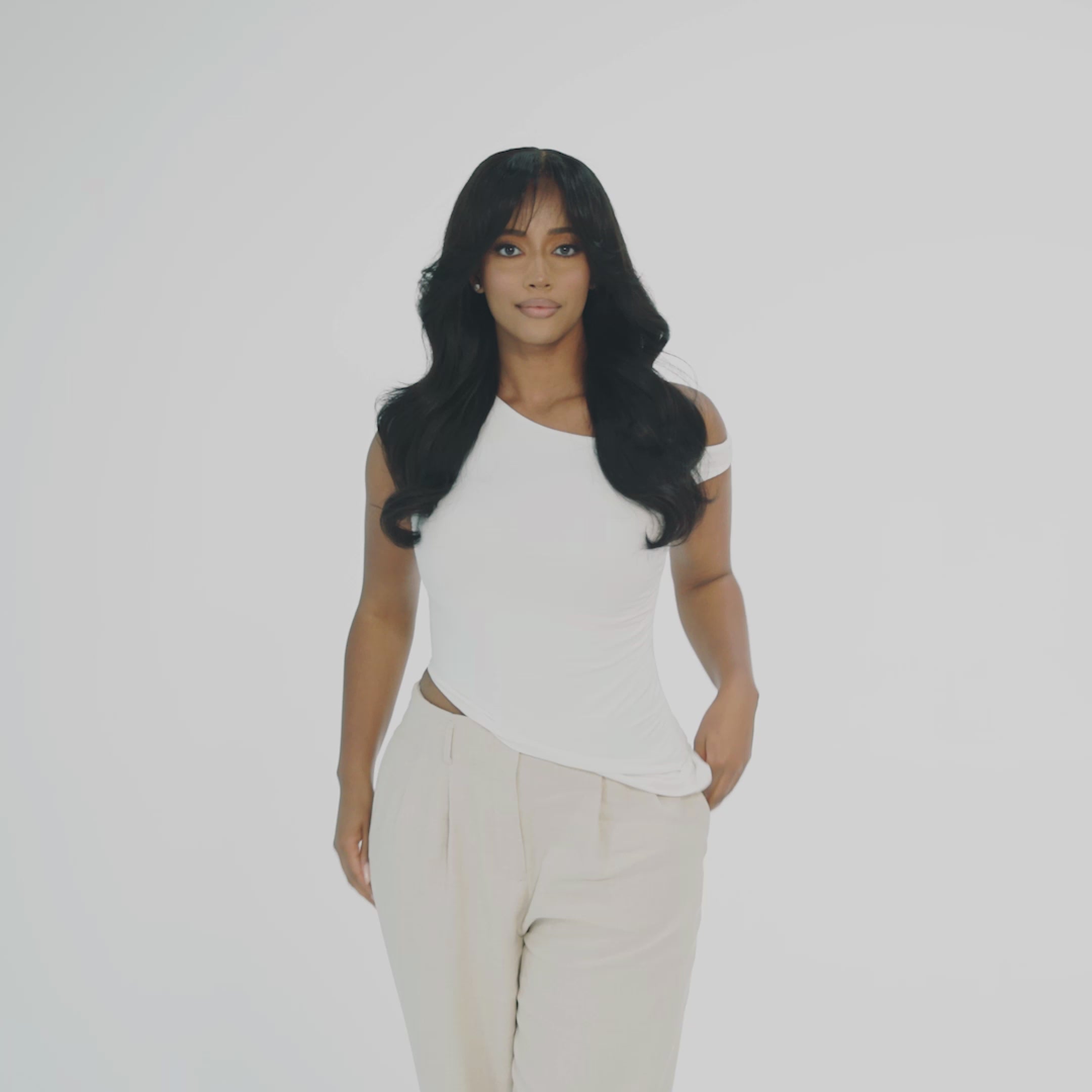 "Model wearing a wig that look extremely natural. This wig is designed for alopecia, hair loss, fashion, or religious reasons. The wig is moderate length is layered and features face framing curtain bangs. It is showcased against a white studio background. The model has a natural, soft glam makeup look.