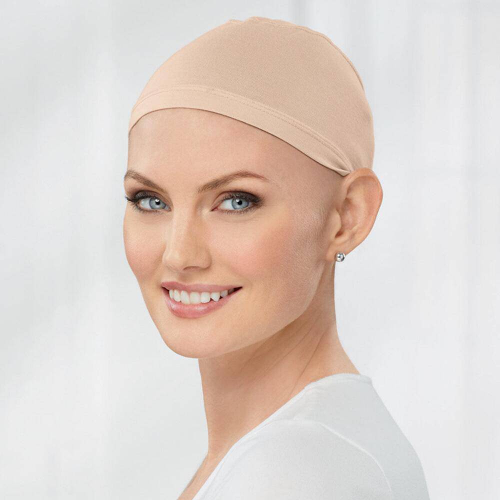 Woman smiling wearing a tan bamboo cap comfort cap on bald head for alopecia and hair-loss.