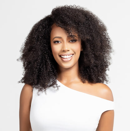 &quot;Model wearing a  afro or kinky texture wig with a side part. This wig is designed for alopecia, hair loss, fashion, or religious reasons. The wig features voluminous, bouncy curls and is showcased against a white studio background. The model has a natural, soft glam makeup look.